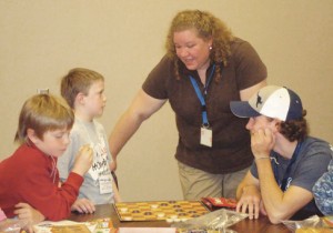 The Creek\'s director, Melanie Pfaff, talks with children at a game table. The program offers after-school care for intermediate-level students.