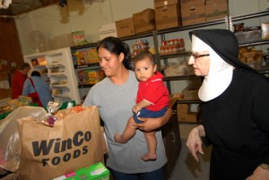 Volunteer Sr. Blanche Smith, right, assists a young mother with a food box at Mission Benedict.                                                 