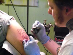 Don Robison works on a tattoo of a wolf on his client’s arm.