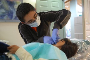 Kennedy High School senior Angel Cardenas flosses St. Mary Elementary School first-grade student Ariana Villa’s teeth. He organized a free dental day for local children for his senior project. 
