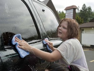Despite the rain, Tessa Davis Cook scrubs down a vehicle during the fundraiser to benefit the Tim and Lori Woods family of Silverton.