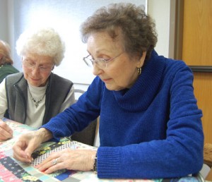Thelma Bourbonnais and Betty Konen work on a 1930s quilt.