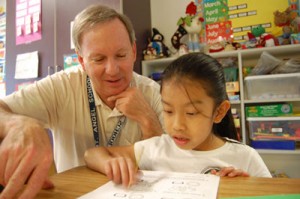 Bill Predeek works with first-grader Galilea Hernandez.