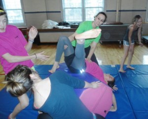 Gymnastics instructor Megan Bonham works with students on the mats to increase flexibility.
