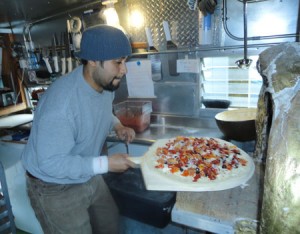 Daniel Jimenez places a pizza in the wood fired oven.