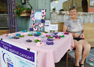 Carolyn Cooley crochets butterflies outside O’Brien’s on Water Street, rewarding donations to money for the American Cancer Society. Photo by Kristine Thomas.