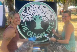 Tonya Smithburg and Kali Dirks painting a mock-up of the Old Oak Tree emblem for the Silverton Arts Festival. They eventually plan to auction it off.  