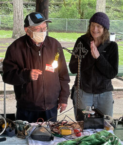 A happy customer claps her hands in delight after a Repair Fair volunteer successfully repaired her antique lamp at last year’s event in Coolidge McClaine Park.