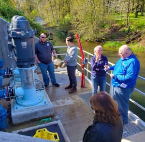 Brad Jensen, left, of the Silverton Public Works Department, Silverton City Manager Cory Misley, Finance Manager Kathleen Zaragoza, J. Wesley Cochran of the federal Economic Development Administration and Shannon Williams of Keller Associates, gather around the new city water pumps during an April 5 walk-through that noted the completion of the project on Silver Creek.      James Day