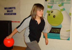 Kaitlin Zwicker bowls at Silver Creek Lanes near a poster reminding customers it is a smoke-free environment. 