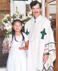 Carolina Cortes has her picture taken with Father Ed after her First Communion.