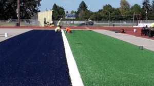 Crews lay down the turf in the north end of the Stayton High football field. The facility should be ready to practice and play on after Labor Day.