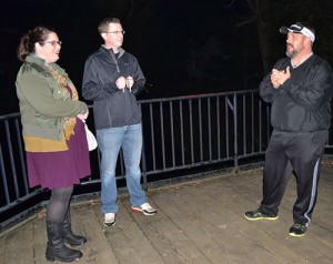 Silverton residents Danie and Marcus Monaghan listen as Dawane Harris tell a tale of a mysterious man who has been spied staring at people on the bridge.