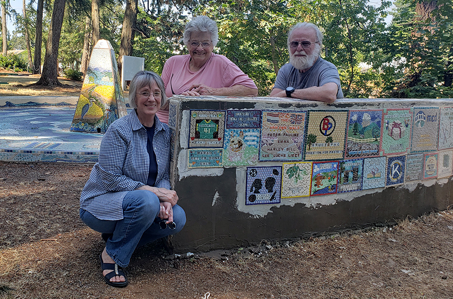 Carol Williams, Mara’d Van Der Wal and Mike Williams perch on the bench where its last tiles were recently installed. 