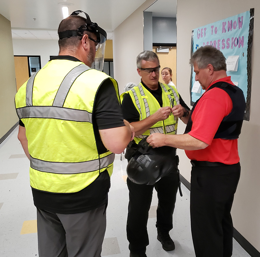 Silverton City Manager Ron Chandler, right, dons a protective vest with assistance from Silverton Police Sgt. JJ Lamoreaux and Chief Jim Anglemier, center.
