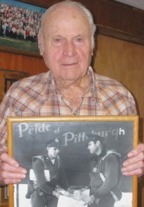 Thurman Smith holds a photo of the Pride of Pittsburgh, in which he and his bombardier look at a map before their flight that earned them the Purple Heart commendation. The bombardier was from Pittsburgh, Penn., and Smith was from Pittsburg, Texas, so they painted the “h” on the plane to accommodate both men’s home towns.          